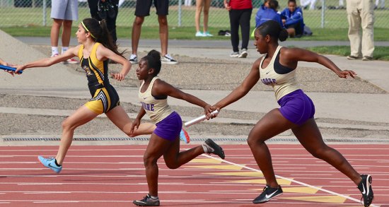 Lemoore's Amaya Sanchez hands the baton off to Iiyanii Jones during the 4x100 relay during Friday night's track and field invitational in Tiger Stadium. The Lemoore team finished third.